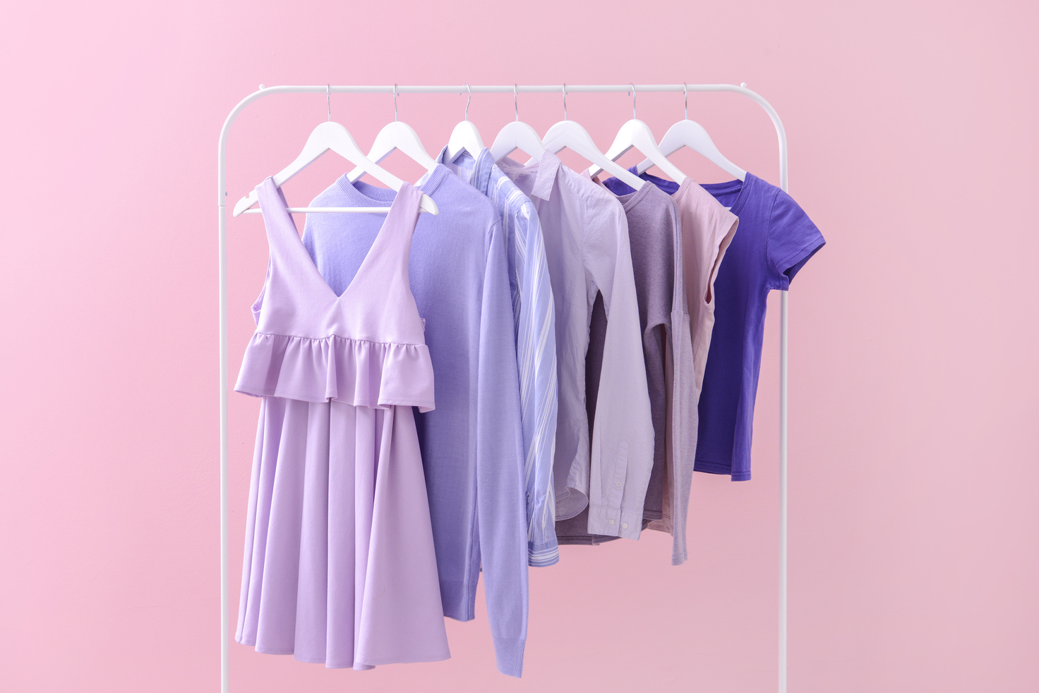 Rack with Hanging Clothes on Color Background